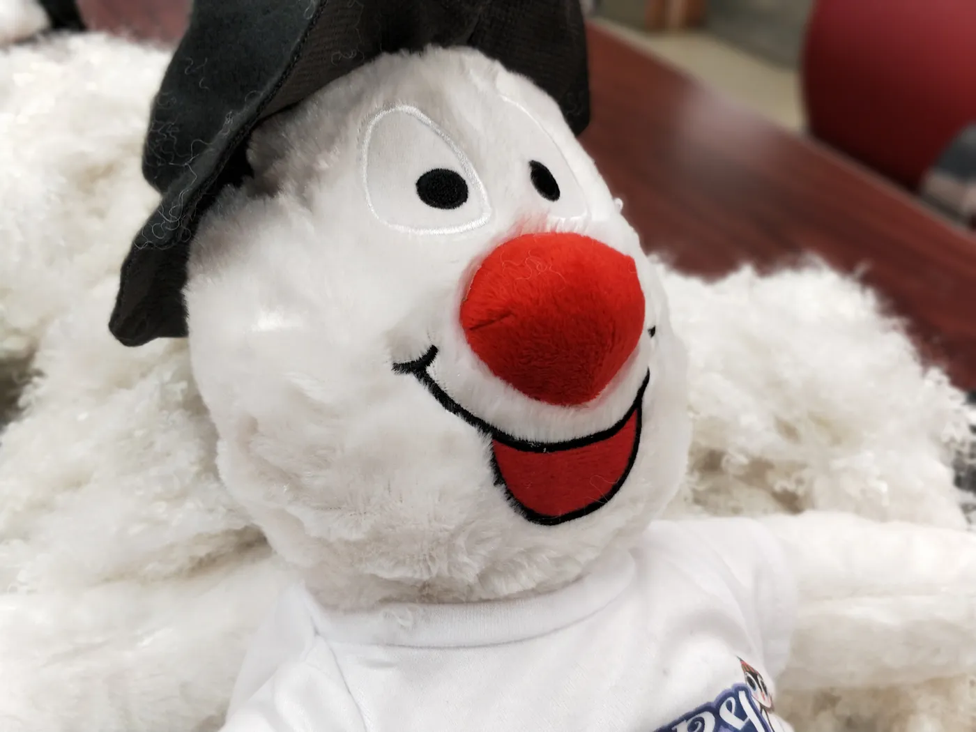 A white snowman plush toy with a black hat
